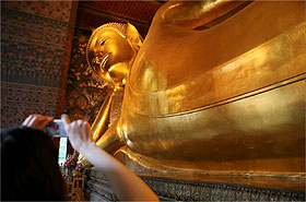 Turista fotografa famoso Buda Reclinado no templo de Wat Pho, atrao em Bancoc