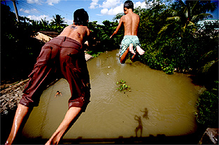 Meninos se jogam em rio no delta do Mekong