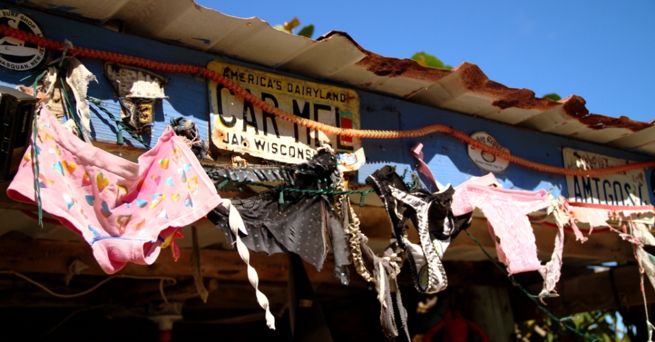 A decoração do bar Bomba's Surfside Shack, bar nas Ilhas Virgens Britânicas, é feita com paredes erguidas com madeiras grafitadas, pranchas de surfe, monitores de computador e uma curiosa decoração com peças íntimas femininas